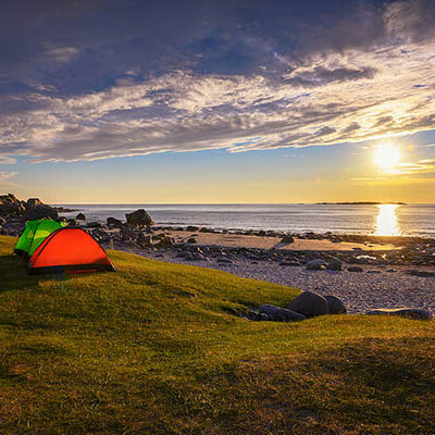 Camping vid strand och solnedgång.